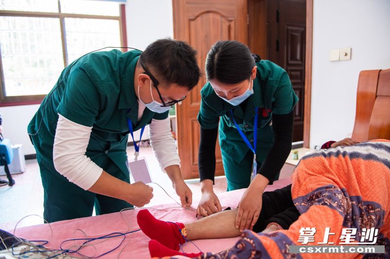 在果园镇杨泗庙社区，医务人员彭永（左）、刘敏（右）给居家老人做理疗。