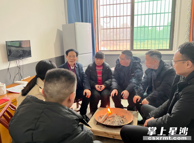 慰问组一行围坐在火炉旁，听江巍的妻子讲述如今的生活。