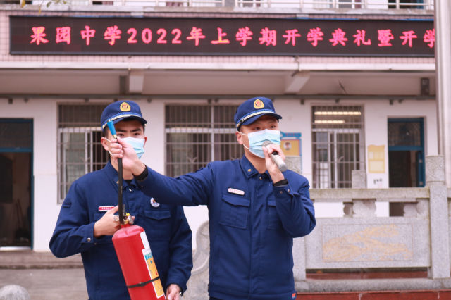 果园镇专职消防队队员正在果园中学升旗台前向学生讲解灭火器的使用