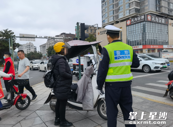 3月18日早高峰,星沙大道三一路口一年轻女子电动车加装伞具行驶被罚。图为交警正在拆卸电动车伞具。 3月18日早高峰,星沙大道三一路口一年轻女子电动车加装伞具行驶被罚。图为交警正在拆卸电动车伞具。