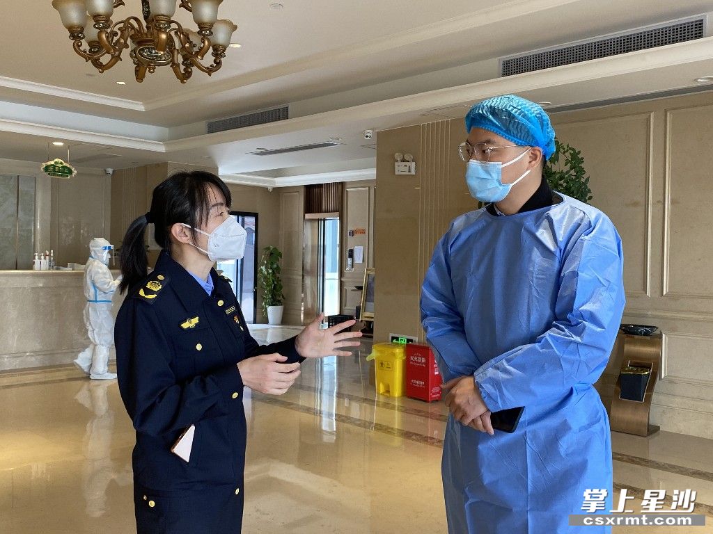 在某隔离酒店，龙双（左）与酒店负责人沟通相关防疫措施和要求。嵇田利 摄