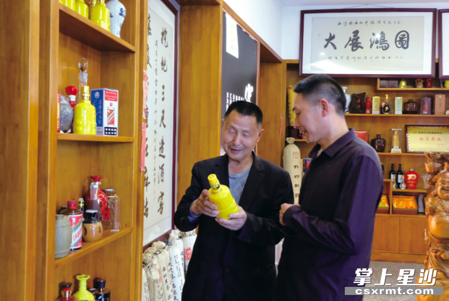 周平（左）在给客户介绍麻姑井酒。李丹 摄
