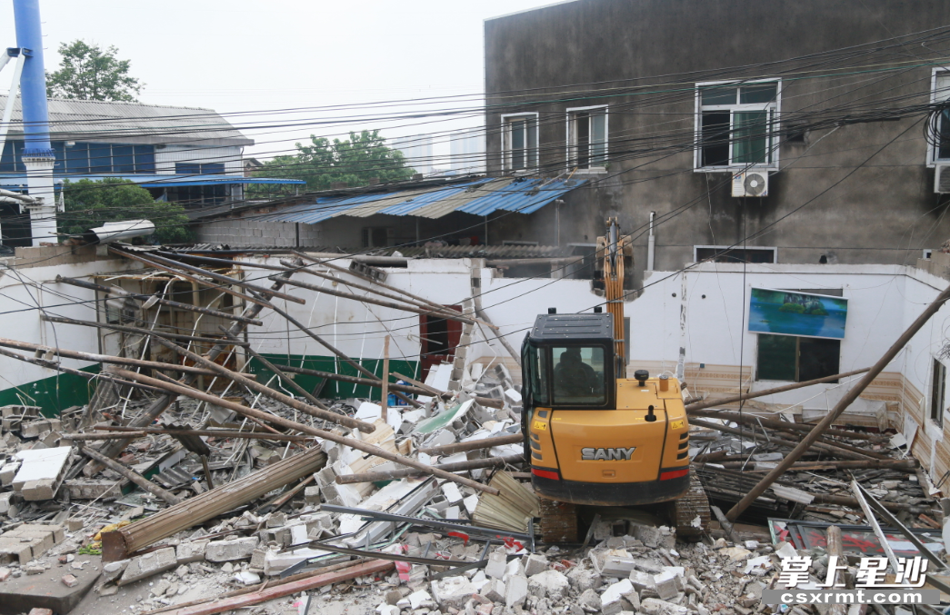 挖掘机正在拆除屋墙. 陈晨 摄