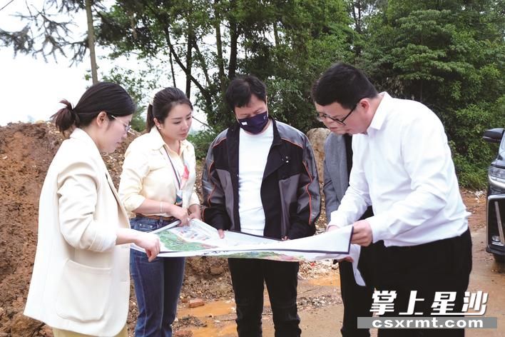 周斌（右一）接待前来考察的客商，拿出松雅湖生态新城规划图给他们介绍地块的区位等情况。李丹 摄