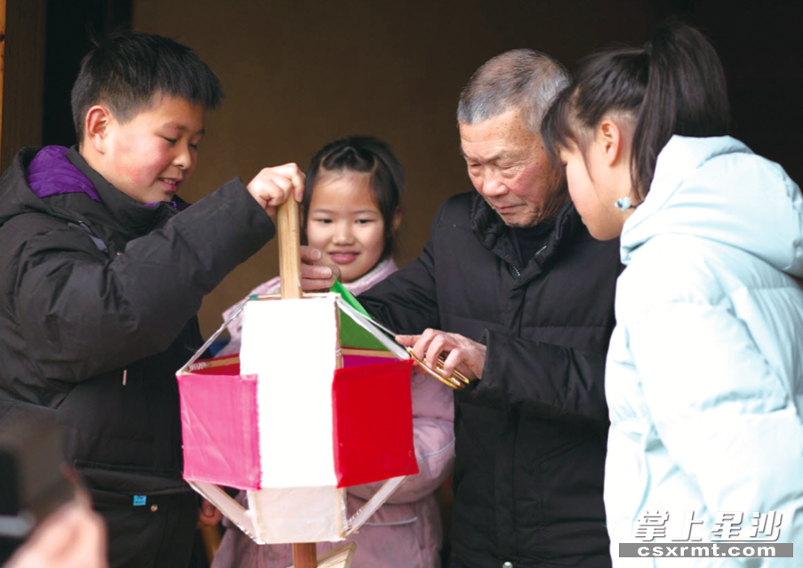 吴乐华（右二）正在教孩子们制作滚灯车。金井镇供图