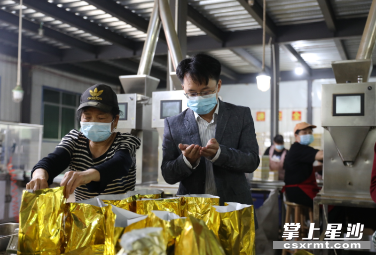 长沙县政协委员周小虎（右）在生产车间查看员工装包茶叶。