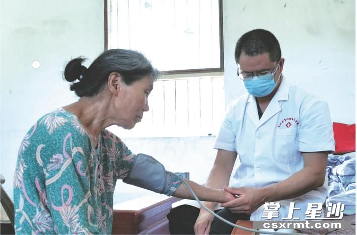 刘展（右）为洪河村高叶塘组年迈居民上门测量血压。易旭 摄