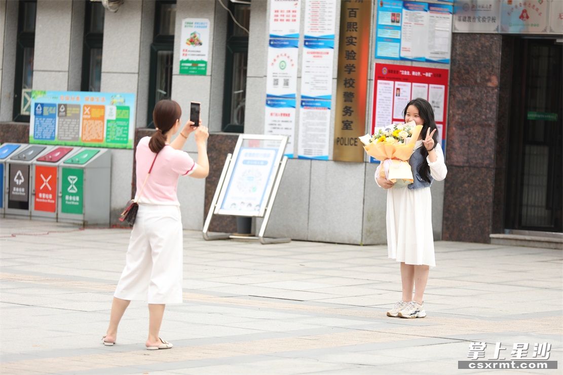 家长黄女士把向日葵送女儿王紫萱后，用手机帮她拍照，定格珍贵的瞬间。李杰 摄