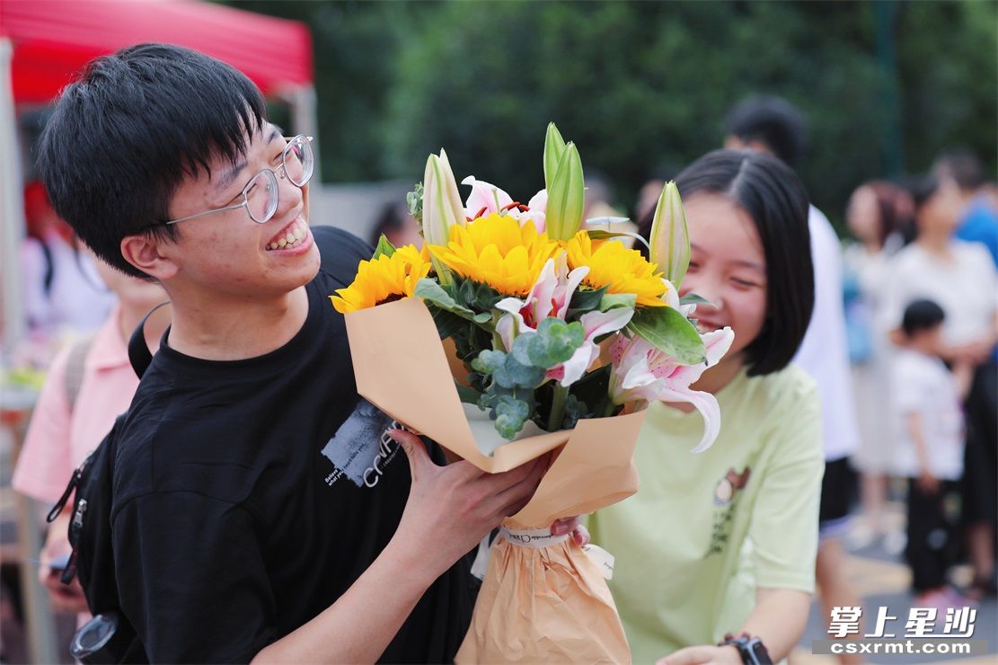 考生陈思旭接过表妹送的鲜花，眼睛笑得眯成一道缝。李杰 摄