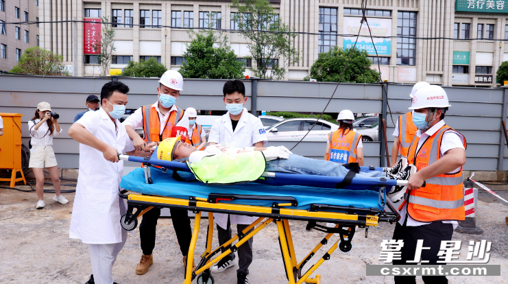 图为医疗救护组配合120急救人员将伤者抬上担架送往医院救治.