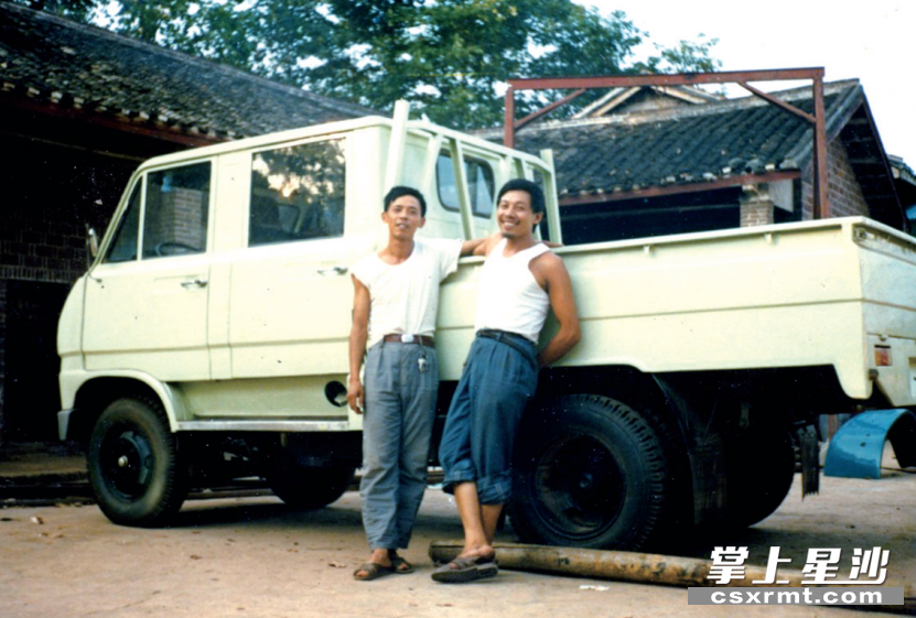 上世纪80年代，湖南同心实业有限责任公司负责人章端祥(右)和唐罗祥在创业初期的厂房门口与刚生产的汽车合影。受访者供图