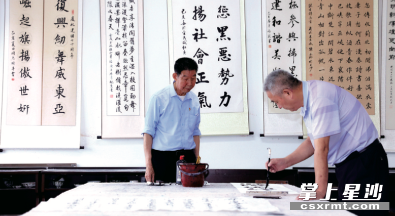为丰富社区老年人精神文化生活，黄苍霖（左）创办老年学校，至今已有学员300余人。图为社区老人在书画室练习书法。 盛磊 摄