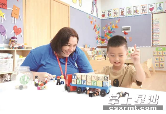 在长沙玮希国际学校，外教老师陪同孩子玩起了玩具。