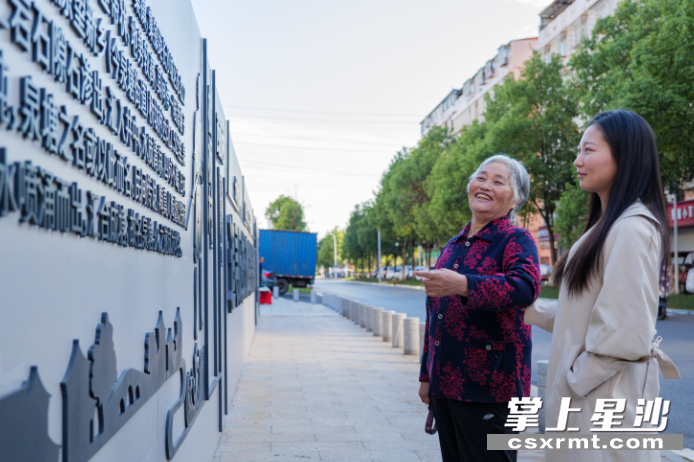 柳伶俐在文化墙前向孙女讲述泉塘老地名的故事。