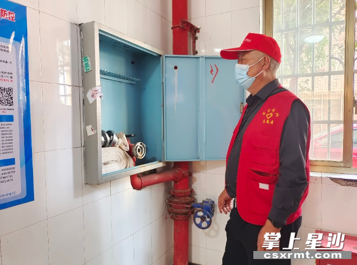 图为楼栋长杨国豪检查所负责楼栋里的消防器材。均为吴涛 摄