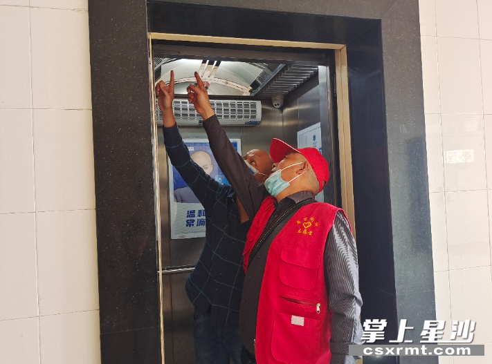 图为电梯维保人员与楼栋长杨国豪沟通解决电梯门存在的问题。