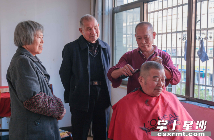图为文检武（右二）在家里给老伙计们剪头发。