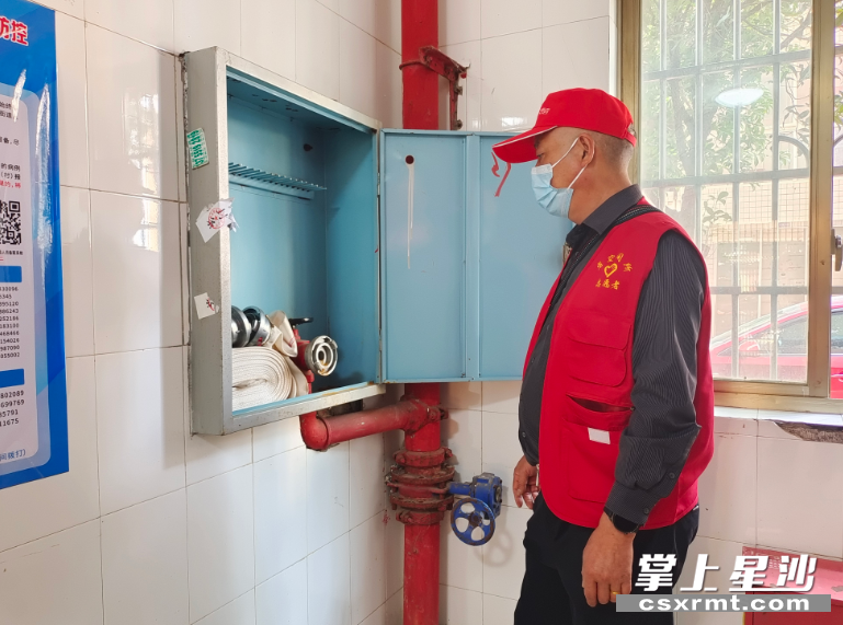 楼栋长杨国豪在检查楼道间的消防水栓。