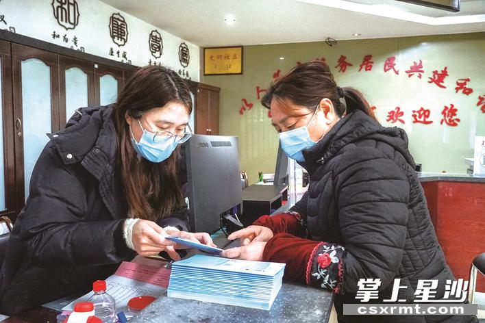 星沙街道望仙桥社区工作人员柳丹（左）正为居民解读城乡居民医疗缴费相关问题。 刘思源 摄