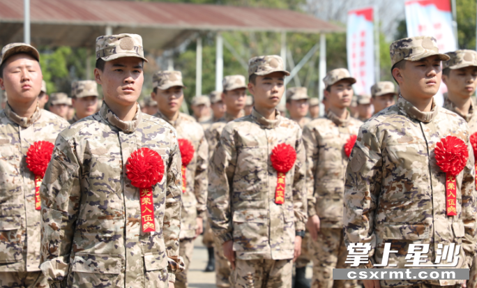 欢送仪式上，预定新兵们个个胸前佩戴大红花，排列整齐接受聆听寄语。