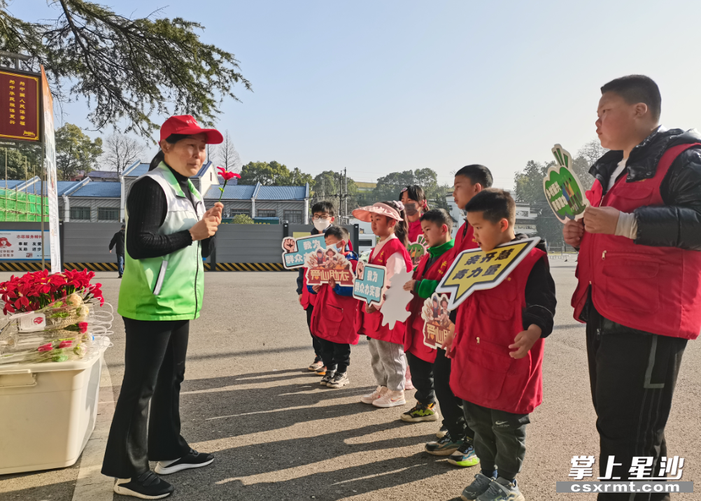 李柳英带领小小志愿者在景区义卖困难群体编织的毛线花。