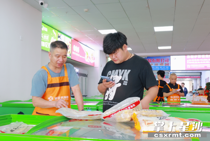 图为超宇食品安井旗舰店，工作人员正帮助顾客选购食材。均为文雅丽摄