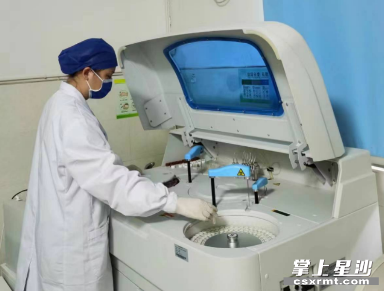 医生在进行生化分析仪相关操作。