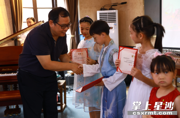 民建中南大学委员会组委李慧中为学生们颁发表演奖励证书。