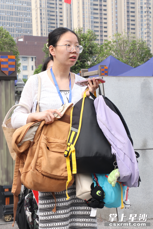 在长沙县特立中学考点外，一送考老师手拿多个背包，为考生们高考做好“后勤保障”。苏铃惠 摄