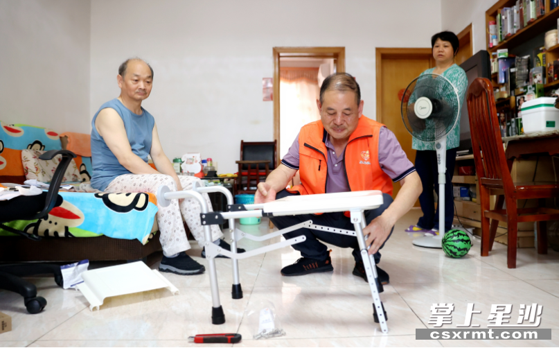 图为工作人员在为孙建辉老人安装折叠坐便椅，方便他日常入厕。 盛磊 摄
