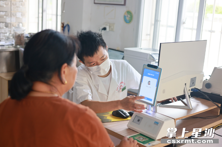 图为村民通过医保刷脸设备完成报账结算。