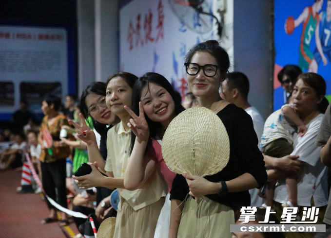 夏日炎热，前来观看篮球赛的观众笑容满面。