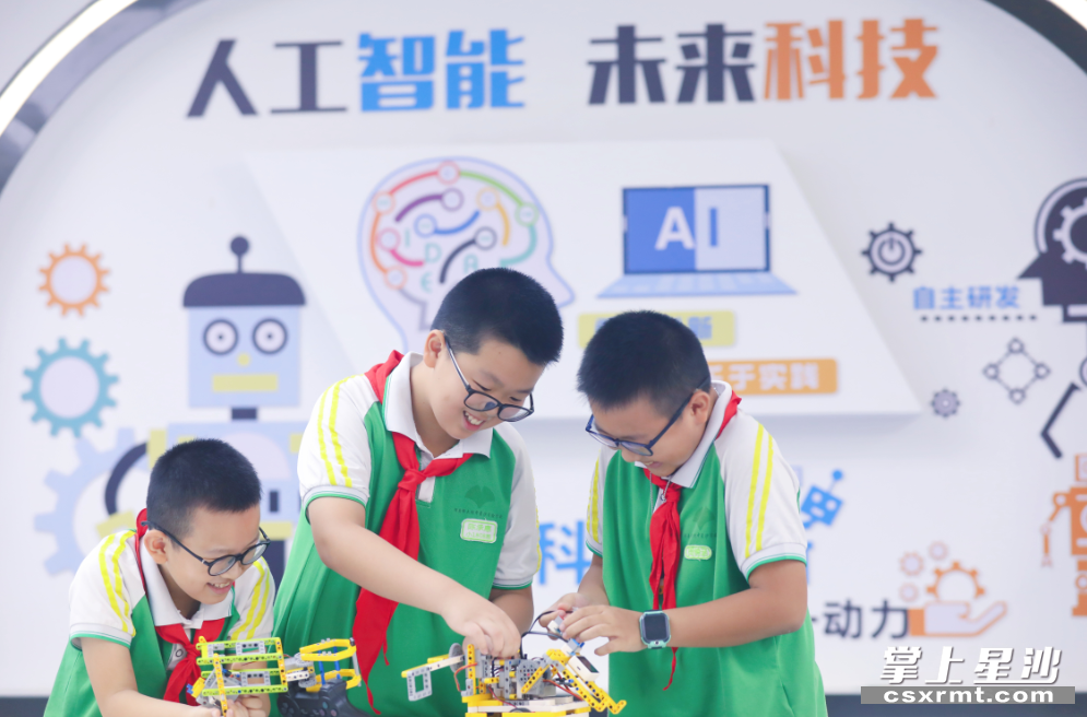 陈承惠（中）、段凯杰（左一）、周锦涵（左三）在学校科创中心练习机器人操控。均为 李杰 摄