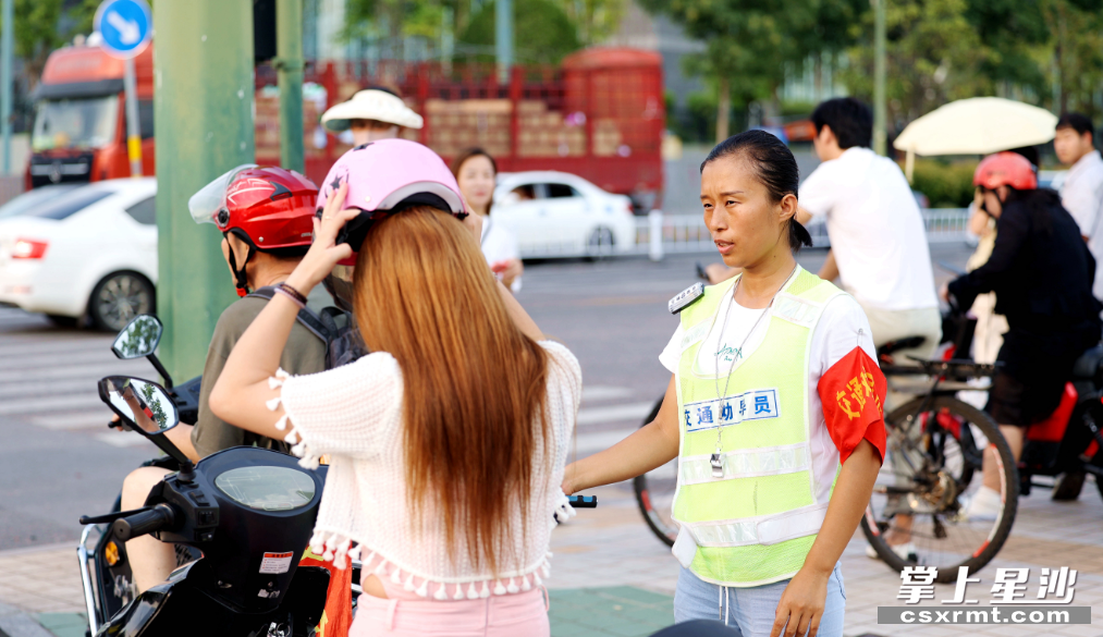 泉塘街道志愿者罗玛莉在漓湘路东四路口开展交通劝导时看到一电动车驾驶人未戴头盔，立即提醒其改正。均为盛磊 摄