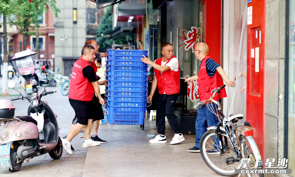泉塘街道居民邓爹带领的海德星锋志愿服务队巡查发现小区沿线有门店占道堆物，立即将物品搬进店内。