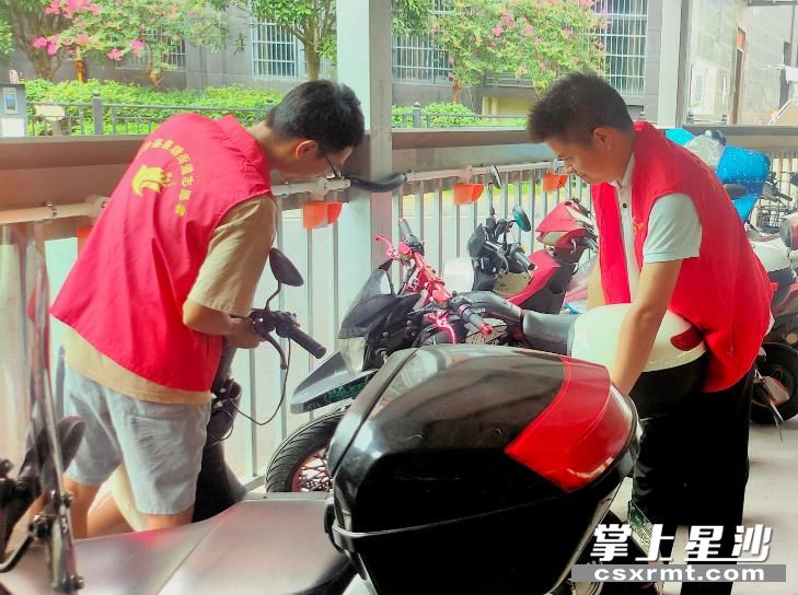 居民代表罗聪（右一）和社区工作人员李迪正在电动车棚规范乱停放问题。泉塘街道 供图