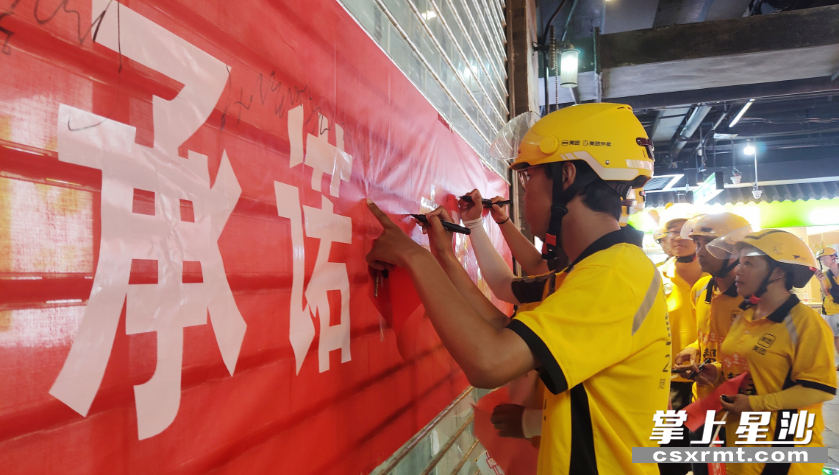 外卖小哥们纷纷在横幅上签字，承诺做一名文明、安全、高素质的驾驶员。