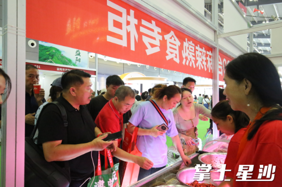 位于长沙县星沙街道的湖南何敖魁食品有限公司展区前试吃观众颇多。均为吴俊贤 摄