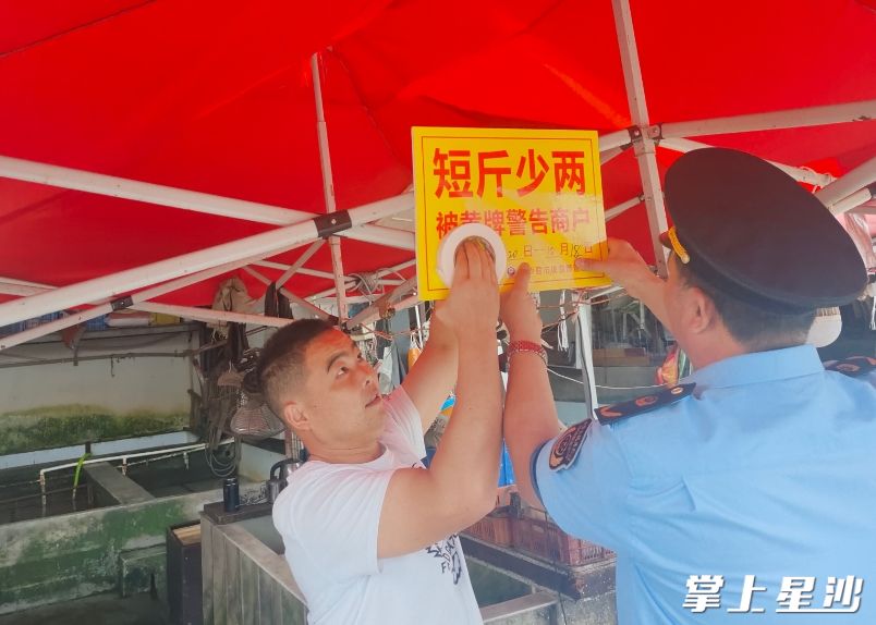 图为市监执法人员与市场管理方为涉事经营户张贴标示牌。县市监局供图