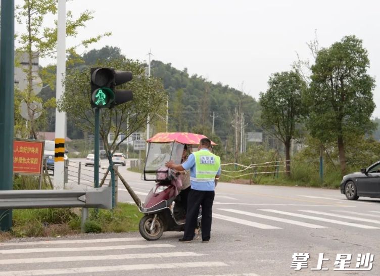 国庆假期间，长沙县交警在路口劝导未戴头盔的电动车驾驶员。