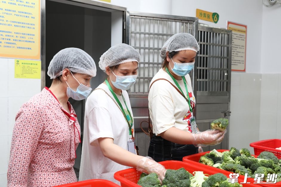 长沙县六艺天骄幼儿园膳食委员会成员对食堂配送的蔬菜进行检查，确保食材新鲜。