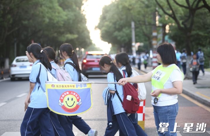 在天华中学校门口，家长志愿者守护学生安全过马路。