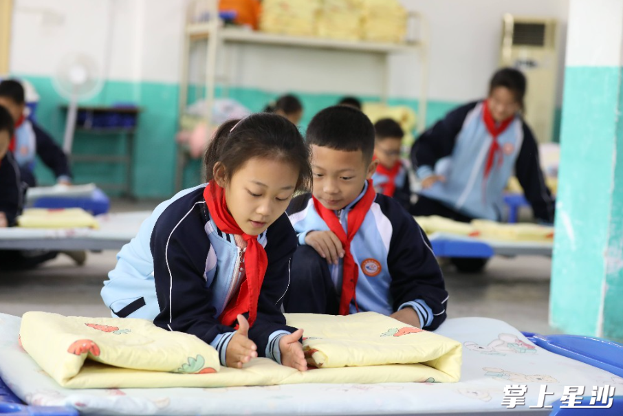 学生正在学习叠被子。