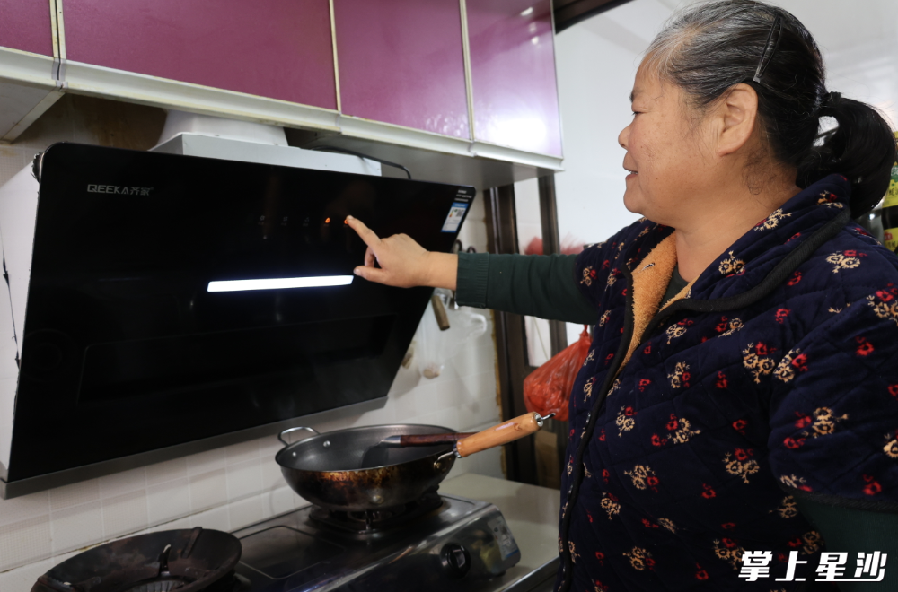 图为周新民使用新装的抽油烟机。