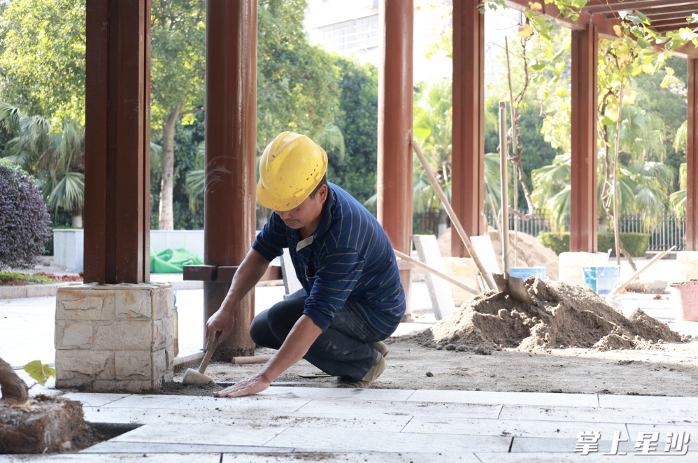 图为工人重新铺设小区公园地砖。