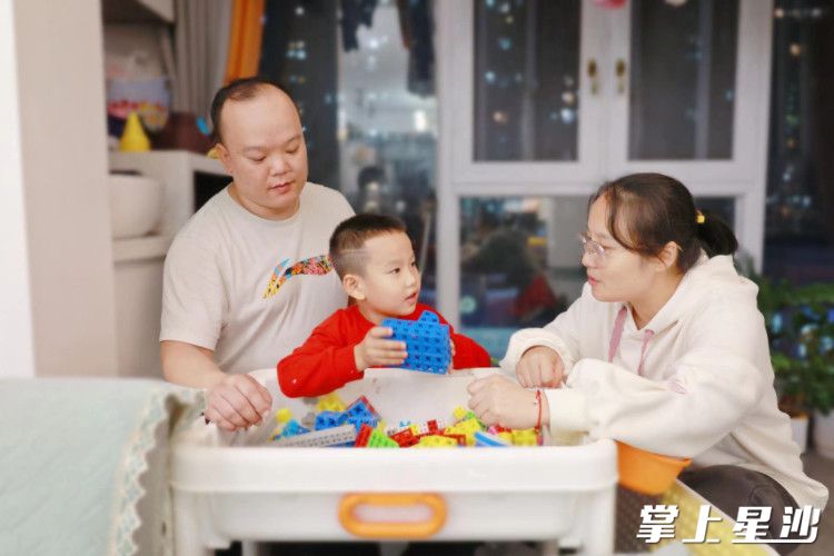 李理和妻子张金凤陪孩子搭积木，一家三口其乐融融。文雅丽 摄