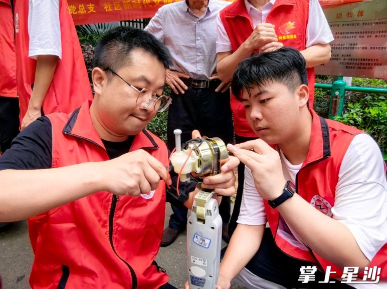 王彬（左一）带领大学生志愿者在开展家电维修活动。泉塘街道供图