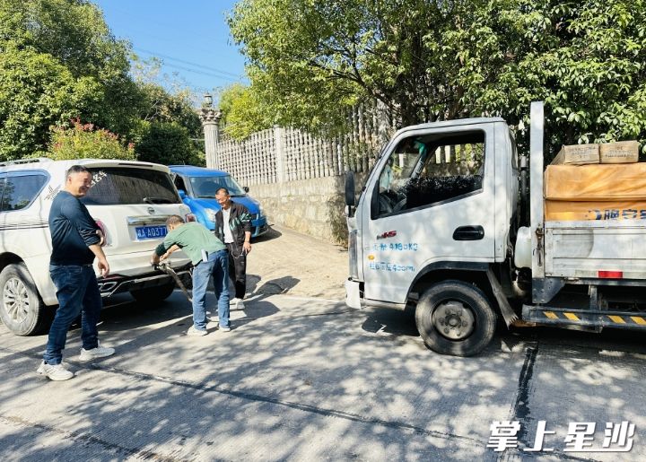 杨栋委与社区工作人员将被困车辆拖至安全地带。