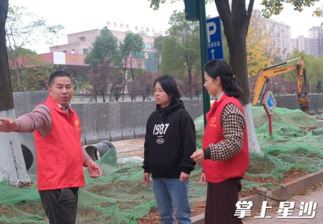 小区联合党支部书记乐永春、党员胡银在小区南门施工现场为居民介绍工程进度。