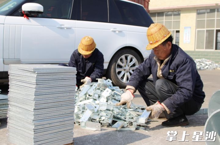 在鑫胜电力车间外，工作人员在摆放器材部件。